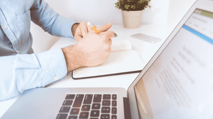 Man working on laptop and writing in journal